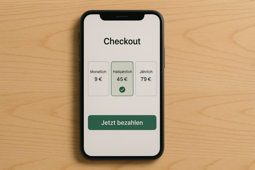 Smartphone auf Holztisch zeigt Checkout-Seite mit drei Preisoptionen: monatlich 9 €, halbjährlich 45 € (vorausgewählt) und jährlich 79 €, darunter grüner Button „Jetzt bezahlen“.