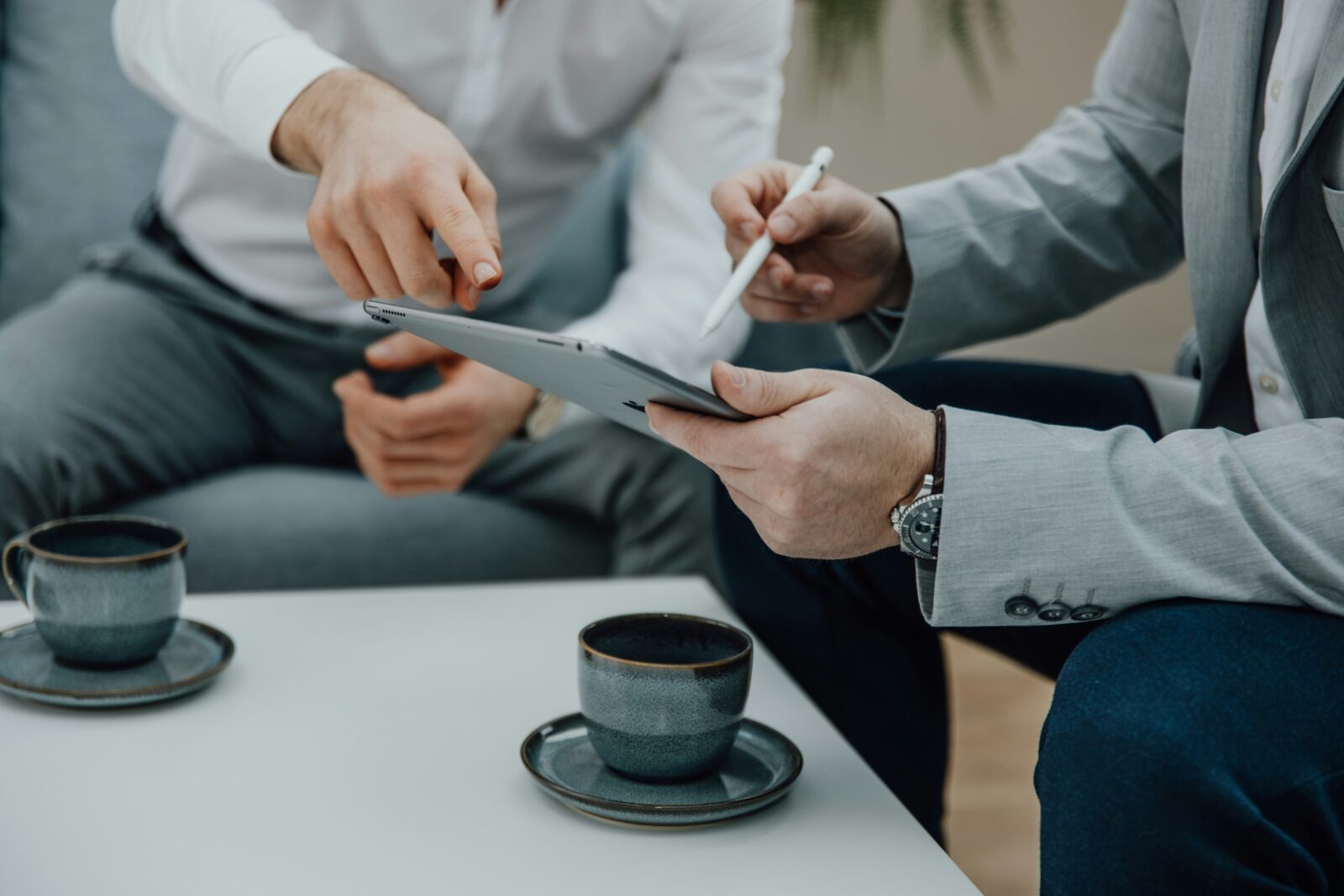 Zwei Personen in Business-Kleidung besprechen Inhalte auf einem Tablet, während zwei Kaffeetassen auf dem Tisch stehen – Titelbild des Blogbeitrags „Fünf spannende Digital Nudging Methoden“ auf der Convertly-Website.