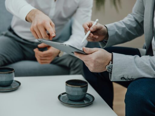 Zwei Personen in Business-Kleidung besprechen Inhalte auf einem Tablet, während zwei Kaffeetassen auf dem Tisch stehen – Titelbild des Blogbeitrags „Fünf spannende Digital Nudging Methoden“ auf der Convertly-Website.