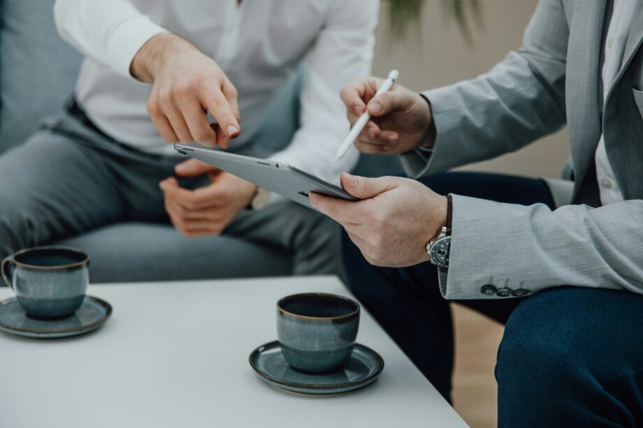 Zwei Personen in Business-Kleidung besprechen Inhalte auf einem Tablet, während zwei Kaffeetassen auf dem Tisch stehen – Titelbild des Blogbeitrags „Fünf spannende Digital Nudging Methoden“ auf der Convertly-Website.